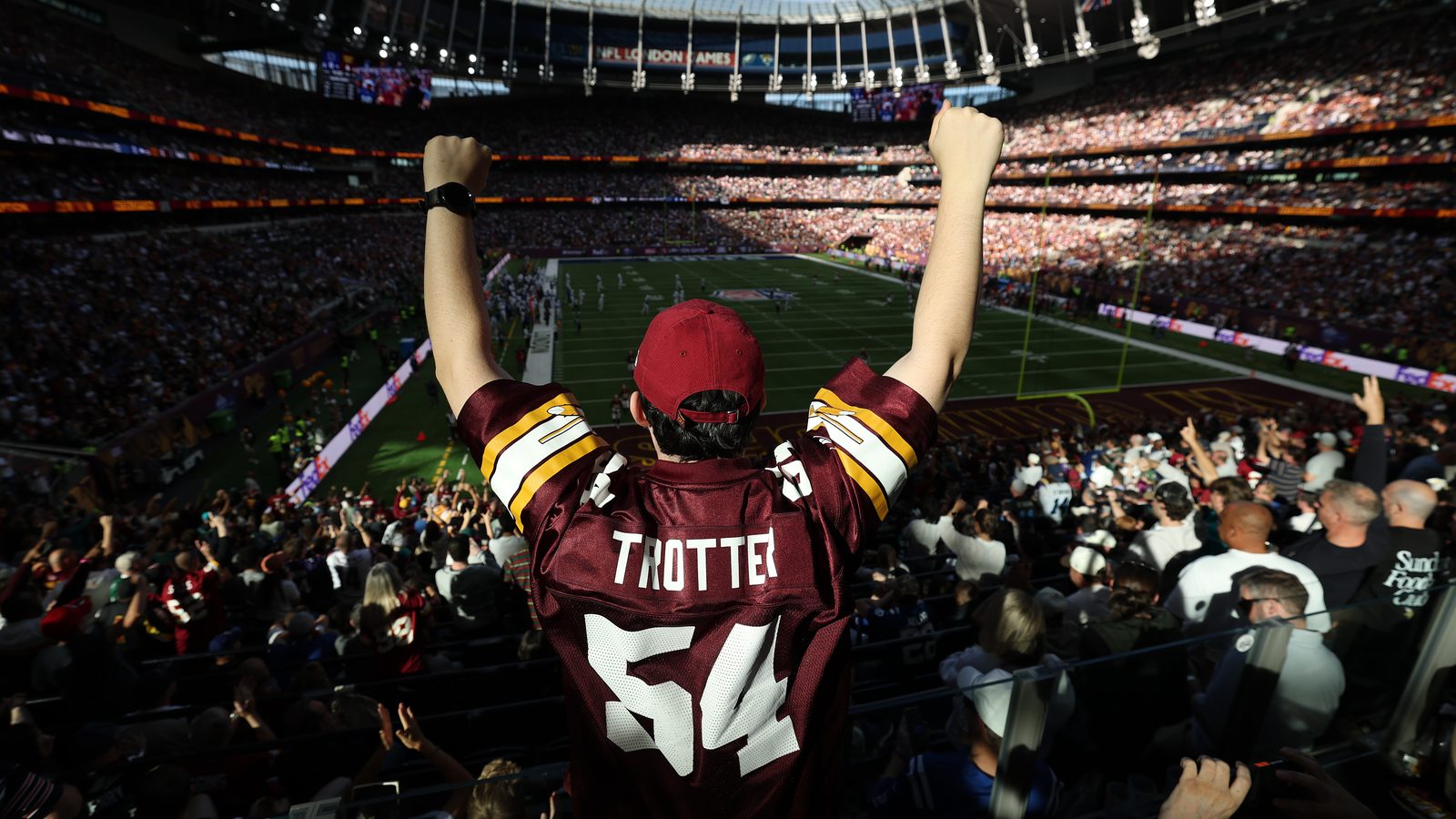 An NFL fan with arms raised at the Tottenham Hotspur Stadium