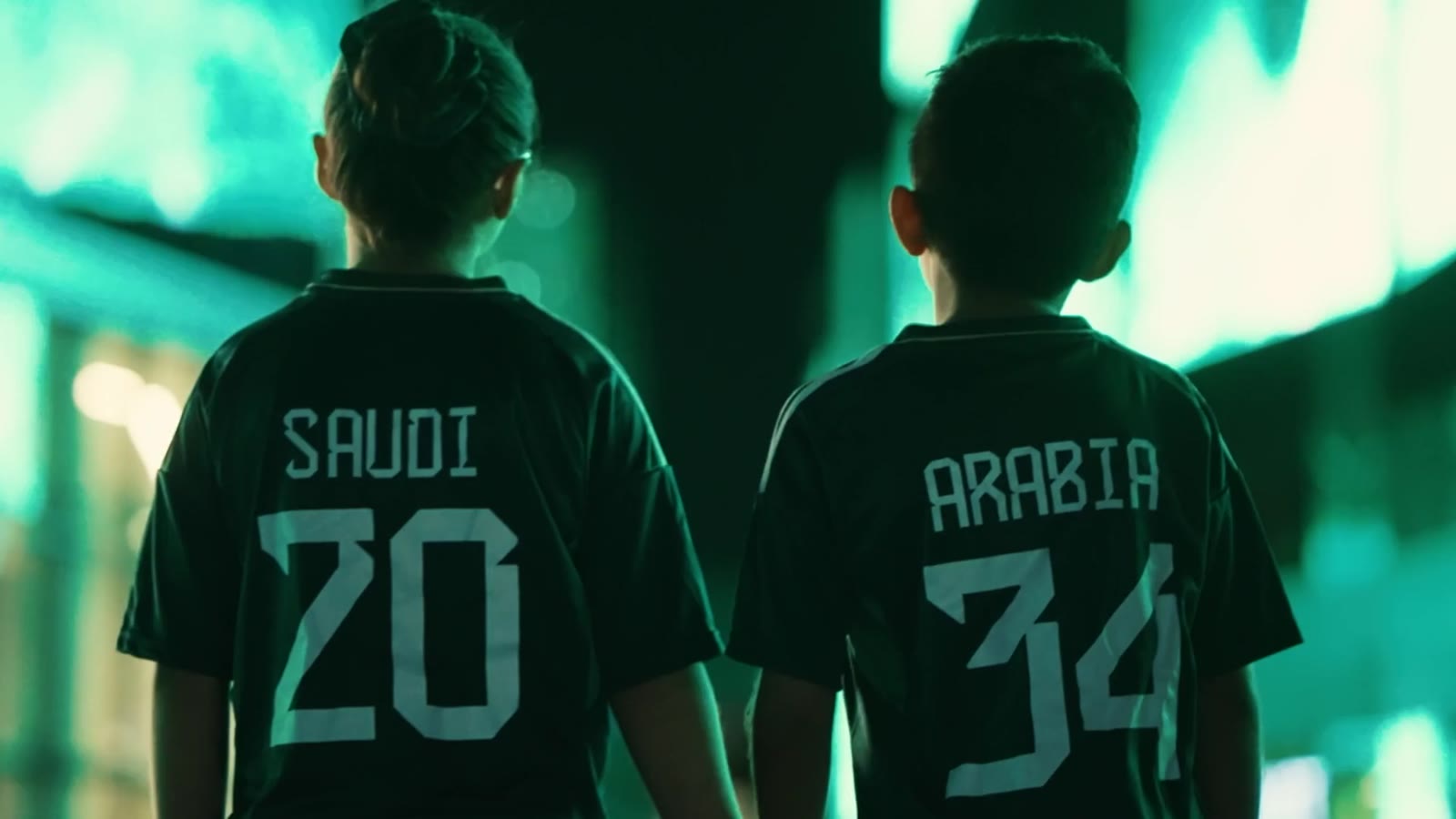 Two boys from behind in shirts reading SAUDI 20 and ARABIA 34